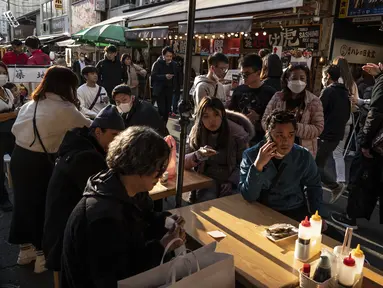 Orang-orang menunggu untuk makan makanan laut di area "pasar ikan luar" Tsukiji di Tokyo pada 28 Desember 2022. Menjelang liburan Tahun Bar, turis asing dan penduduk lokal berkunjung ke pasar itu untuk menikmati hidangan bermacam makanan laut. (AFP/Richard A. Brooks)
