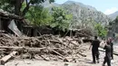Warga mengamati bangunan rumah yang rusak akibat dihantam banjir bandang di Ursoon, daerah terpencil Chitral di Pakistan utara, Minggu (3/7). Banjir bandang akibat hujan lebat yang lama itu telah menewaskan sedikitnya 43 orang. (GUL HAMAAD Farooqi/AFP)