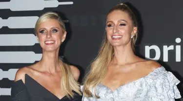 Paris Hilton bersama adiknya Nicky Hilton Rothschild tersenyum saat berpose menghadiri Savage x Fenty selama New York Fashion Week di Barclays Center di New York City (10/9/2019). Paris Hilton tampil anggun memamerkan tubuh langsingnya dalam balutan gaun mini biru. (AFP Photo/Jim Spellman)