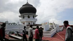 Sejumlah orang melihat kondisi masjid yang runtuh usai gempa di Meuredu, Pidie Jaya, Aceh, Rabu (7/11). Selain meruntuhkan bangunan, gempa bumi berkuatan 6,4 SR ini telah menelan banyak korban jiwa. (Antara Foto / Irwansyah Putra / via REUTERS)
