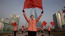 Kelompok Serikat Wanita Sosialis mengibarkan bendera saat melakukan propaganda di depan Hotel Ryugyong, Pyongyang, Korea Utara, Sabtu (9/3). Mereka melakukan aksinya di lokasi-lokasi strategis sekitar Pyongyang pada hari Senin-Sabtu. (Ed Jones/AFP)