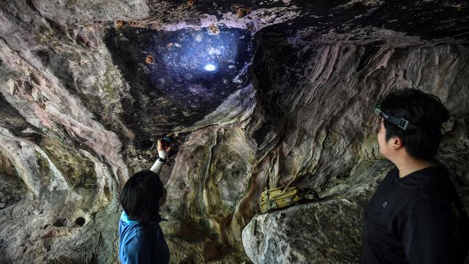 Arkeolog dari Departemen Seni Rupa di Ratchaburi melihat lukisan gua yang baru ditemukan di taman nasional Khao Sam Roi Yot di pesisir provinsi Prachuap Kiri Khan (10/9/2020). Ini merupakan penemuan menakjubkan bagi tim arkeolog Thailand. (AFP/Lillian Suwanrumpha)