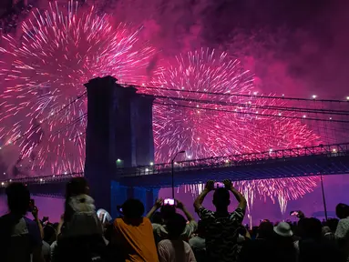 Orang-orang menyaksikan pertunjukkan kembang api di sisi timur Manhattan selama perayaan Hari Kemerdekaan Amerika Serikat atau yang dikenal sebagai Fourth of July di New York, Kamis (4/7/2019). Di Amerika Serikat sendiri, 4 Juli ditetapkan sebagai hari libur nasional. (AP Photo/Jeenah Moon)