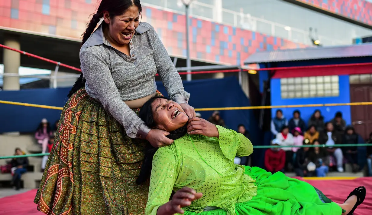 Pegulat Bolivia, Ana Luisa Yujra (kiri), bertarung dengan lawannya, Lidia Flores di atas ring gulat di El Alto, pada 24 November 2019. Di Bolivia ada sebuah atraksi gulat yang diperankan perempuan dengan menggunakan busana khas warga Bolivia. (Ronaldo SCHEMIDT / AFP)