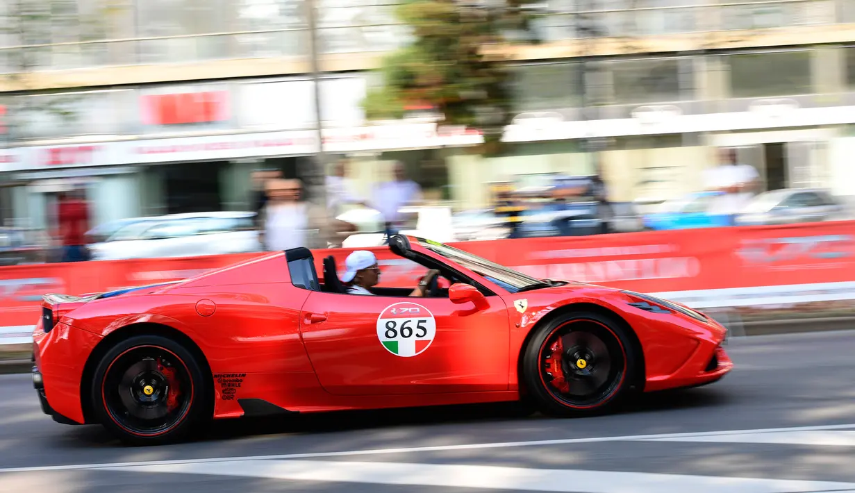 Pengendara melaju membawa mobil Ferrari saat perayaan ulang tahun Ferrari ke-70 di Corso Sempione di Milan, Italia (8/9). Dalam acara ini sekitar 500 mobil Ferrari dari berbagai tipe pamerkan. (AFP Photo/Miguel Medina)