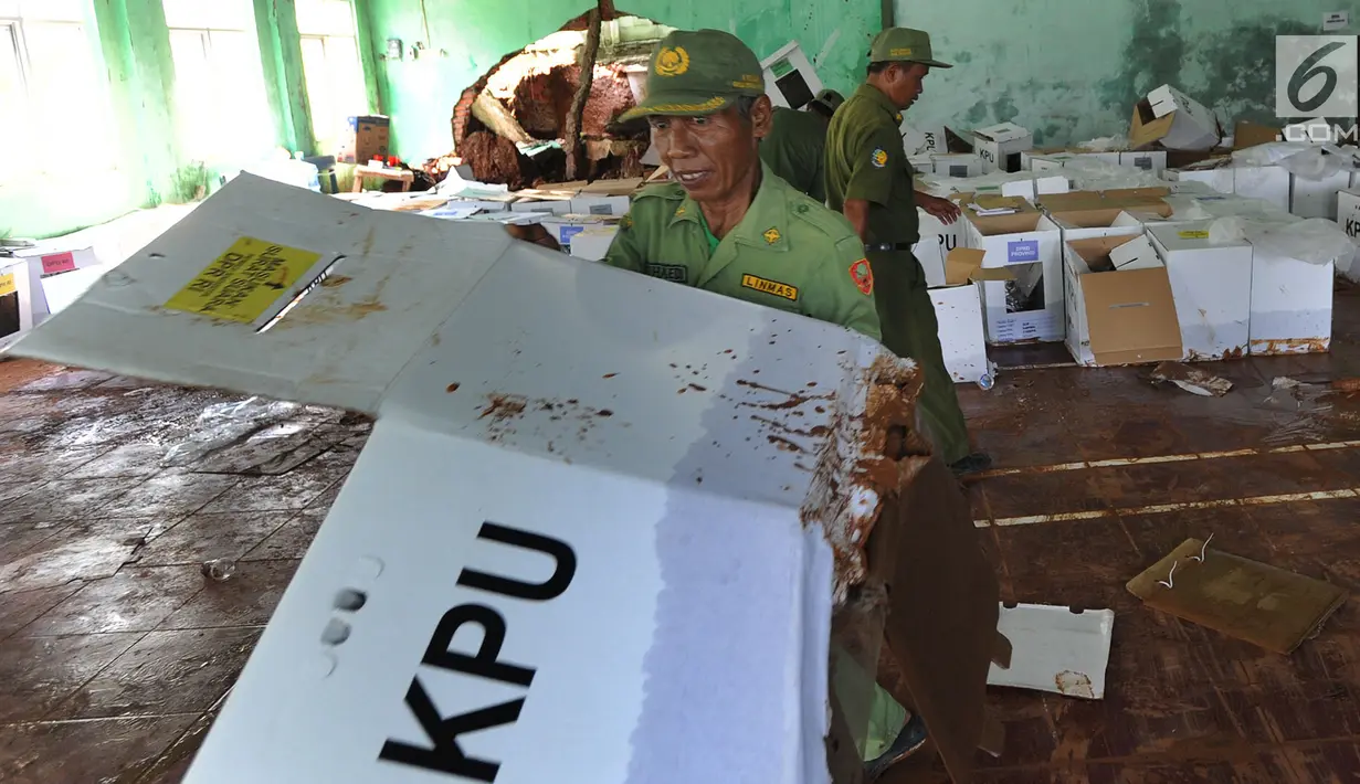 Petugas Linmas menyelamatkan kotak suara kardus yang sebagian rusak terendam banjir di gudang tempat penyimpanan logistik di Kecamatan Ciseeng, Bogor, Senin (15/4). Lebih dari 600 kotak suara rusak akibat tembok gudang jebol diterpa hujan lebat dan angin kencang semalam. (merdeka.com/Arie Basuki)