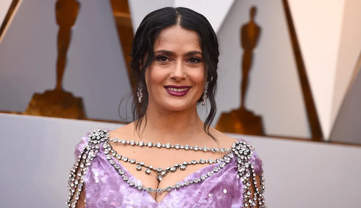 Aktris Salma Hayek berpose untuk fotografer di karpet merah ajang Piala Oscar 2018 atau Academy Award ke-90 di Los Angeles, Minggu (4/3). Kesan classy itu semakin kuat dengan lipstik ungu tua yang dpadukan busana seksinya. (Jordan Strauss/Invision/AP)