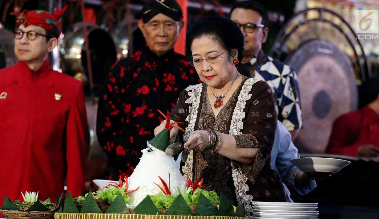 Ketua Umum PDIP Megawati Soekarnoputri memotong tumpeng pada pagelaran wayang kulit dalam rangka HUT PDIP ke-45 di Tugu Proklamasi, Jakarta, Sabtu Malam (27/1). Megawati juga membagikan 45 sepeda gunung kepada penonton.(Liputan6.com/Johan Tallo)