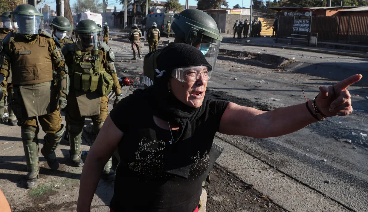 Seorang demonstran saat bentrok dengan polisi di tengah pandemi virus corona Covid-19 selama penguncian wilayah (lockdown) di lingkungan miskin di Santiago, Chili, (18/5/2020). (AP Photo/Esteban Felix)