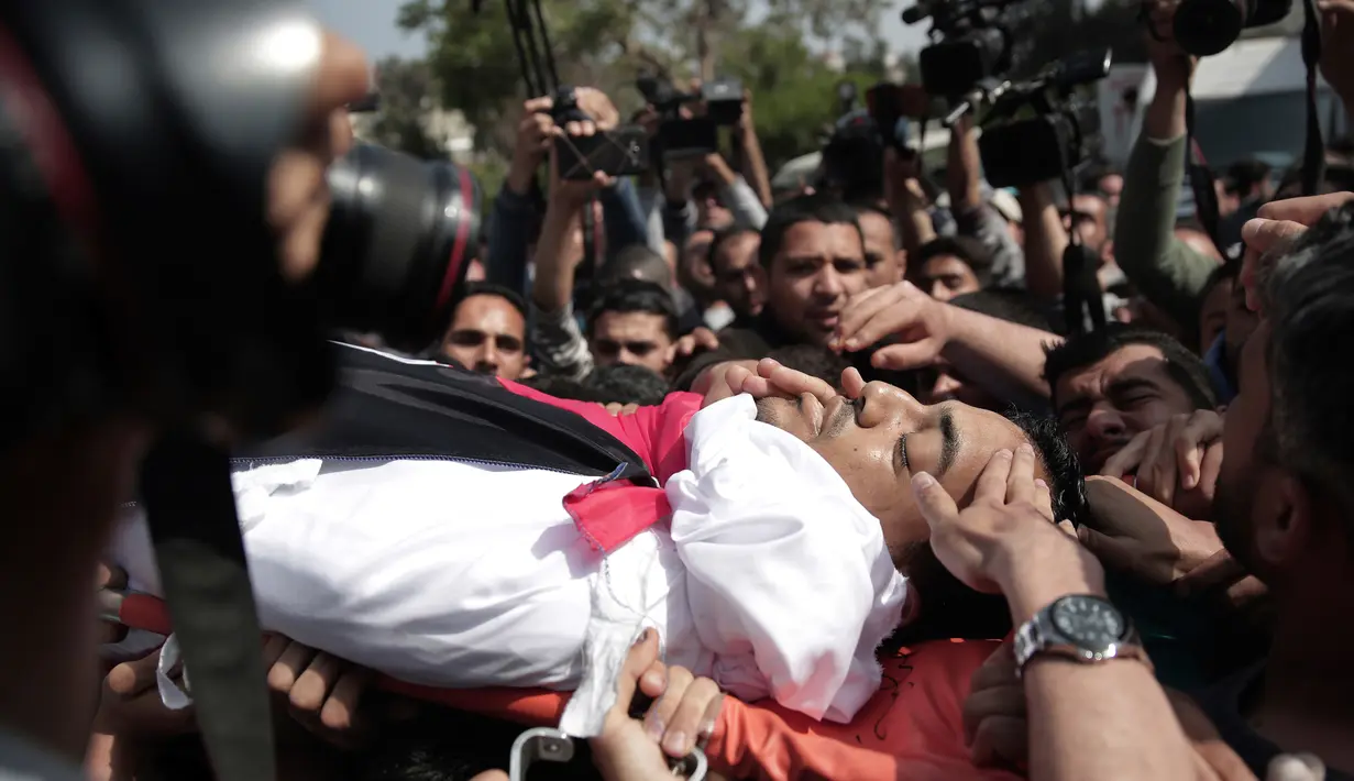 Pelayat membawa jasad seorang wartawan Palestina yang tewas ditembak tentara Israel saat meliput protes di perbatasan Gaza dengan Israel, Sabtu (7/4). Perusahaan media tempat Yasser Murtaja bekerja memastikan kematian wartawannya. (AP Photo/Khalil Hamra)