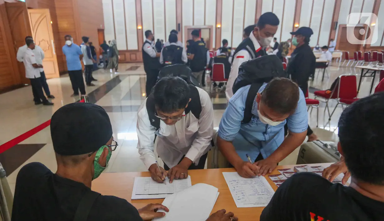 Petugas PPIH mengisi dokumen di asrama haji Pondok Gede, Jakarta, Selasa (31/5/2022). Petugas  PPIH (Petugas Panitia Penyelenggara Ibadah Haji) sebanyak di  828 orang di berangkatkan pada Rabu (1/6/2022) yang di bagi daerah kerja ke Jeddah, Madinah dan Mekkah. (Liputan6.com/Herman Zakharia)