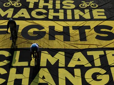 Pesepeda melintas di atas banner yang dibentangkan aktivis Greenpeace dan Bike2Work di Jalan Jenderal Sudirman, Jakarta, Minggu (5/6/2022). Aksi untuk mengkampanyekan penggunaan sepeda sebagai kendaraan ramah lingkungan dan solusi pembangunan Jakarta Kota Ramah Pesepeda. (Liputan6.com/Helmi Fithriansyah)