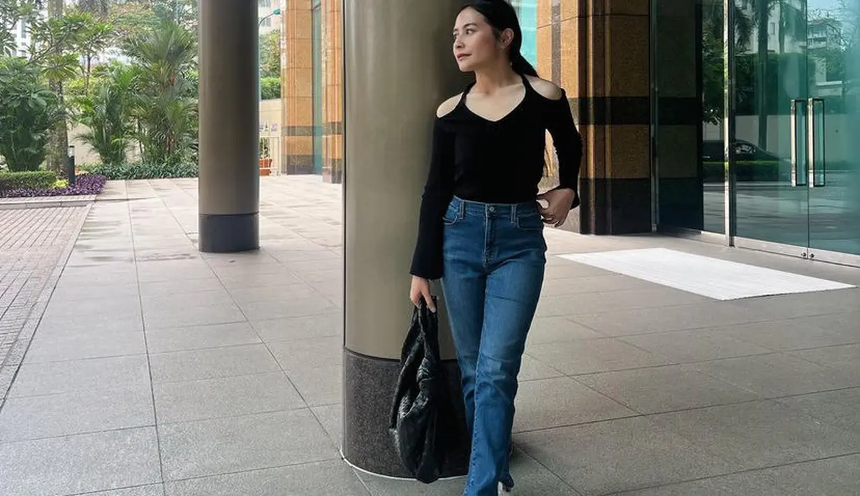Prilly tampil mengenakan atasan cut out pundak hitam lengan panjang dipadukan celana denim panjang. Dalam tampilan tersebut ia terlihat langsing. [@prillylatuconsina96]
