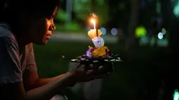 Seorang wanita berdoa sebelum menghayutkan 'krathong' untuk merayakan festival Loy Krathong di sebuah danau di Bangkok, Kamis (22/11). Loy Krathong dirayakan setiap tahun di seluruh Thailand sebagai penghormatan kepada dewi air. (Jewel SAMAD/AFP)