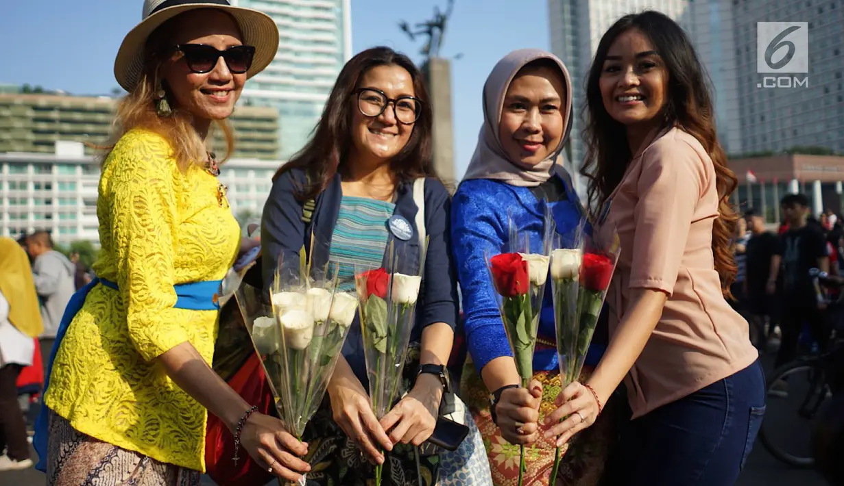 Relawan memegang bunga mawar untuk dibagikan ke pengunjung car free day di kawasan Bundaran HI, Jakarta, Minggu (30/6/2019).  Aksi 1000 bunga mawar itu sebagai bentuk rasa syukur atas kemenangan pasangan Jokowi-Ma'ruf Amin di Pilpres 2019. (Liputan6.com/Immanuel Antonius)