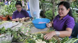 Umat Hindu membuat sesajen jelang perayaan Nyepi di Pura Aditya Jaya, Jakarta, Sabtu (25/3). Sesajen tersebut merupakan simbol persembahan kepada Sang Hyang Widhi Wasa atau Sang Pencipta sebagai bentuk syukur jelang Nyepi. (Liputan6.com/Yoppy Renato)