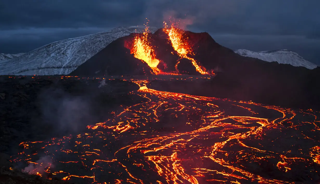 Pemandangan aliran lahar dari letusan gunung berapi di Semenanjung Reykjanes, barat daya Islandia, Senin (29/3/2021). Letusan gunung berapi tersebut masih menarik ribuan orang yang berharap untuk mendekati aliran lahar. (AP Photo/Marco Di Marco)