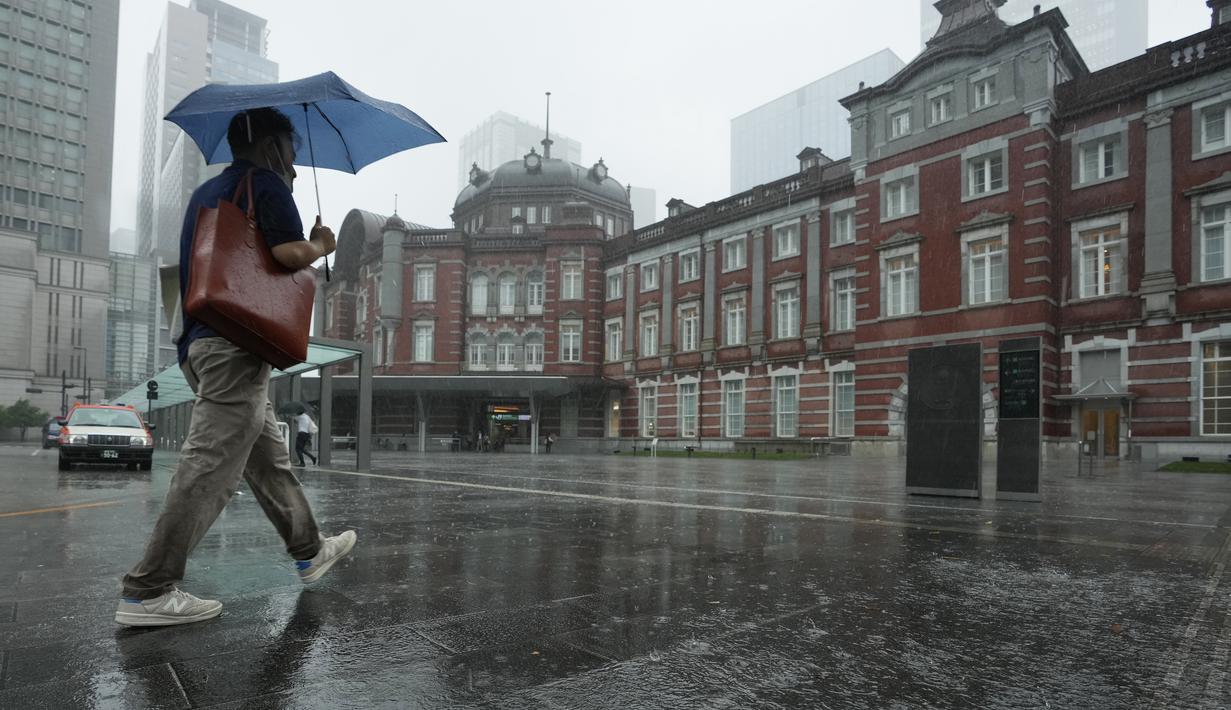 Seorang pria berjalan di tengah hujan menuju stasiun kereta api Tokyo, Selasa (20/9/2022). Pejabat cuaca mendesak orang-orang untuk tetap waspada terhadap tanah longsor, sungai yang meluap, banjir di daerah dataran rendah, angin kencang, dan gelombang tinggi.  (AP Photo/Hiro Komae)