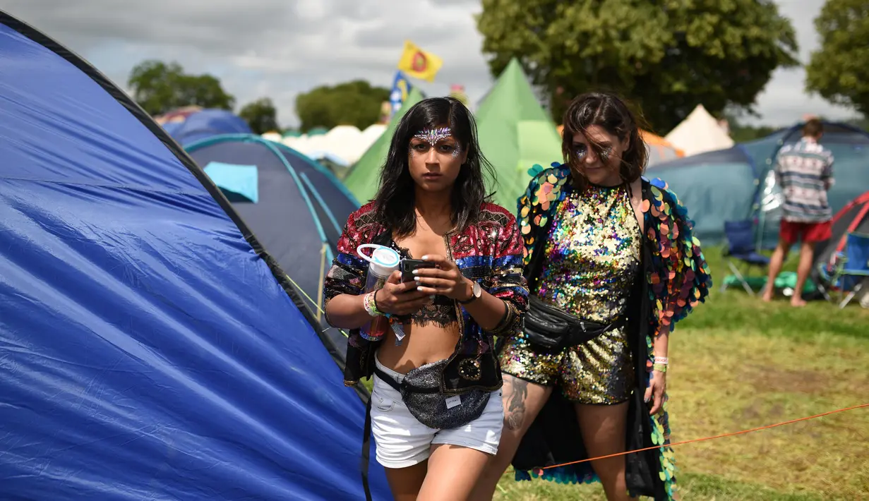 Dua wanita keluar dari tenda selama Festival Glastonbury di Worthy Farm, Somerset, Inggris (30/6/2019). Festival Glastonbury merupakan festival musik paling populer di dunia yang berlangsung lima hari. (AFP Photo/Oli Scarff)