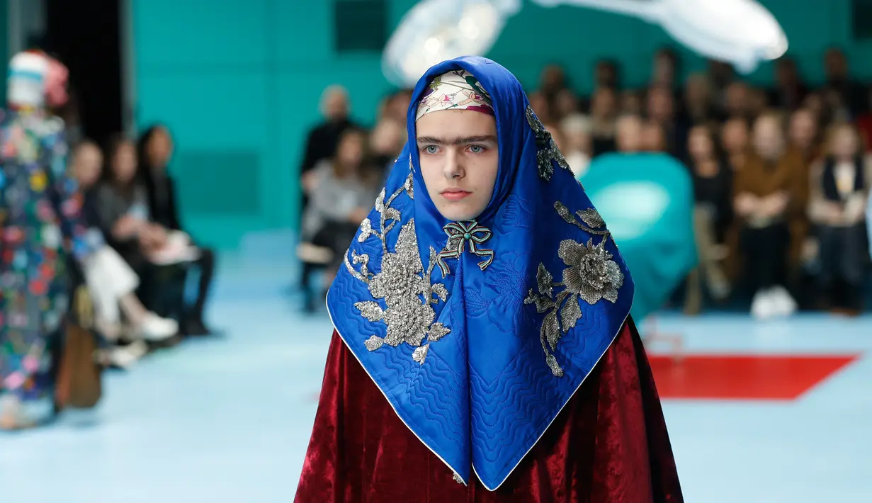 Seorang model dengan scarf menyerupai hijab di kepalanya menampilkan koleksi terbaru Gucci FW18 dalam Milan Fashion Week 2018, Rabu (21/2). Hadirnya model yang memakai scarf menyerupai hijab itu mencuri perhatian. (AP Photo/Antonio Calanni)