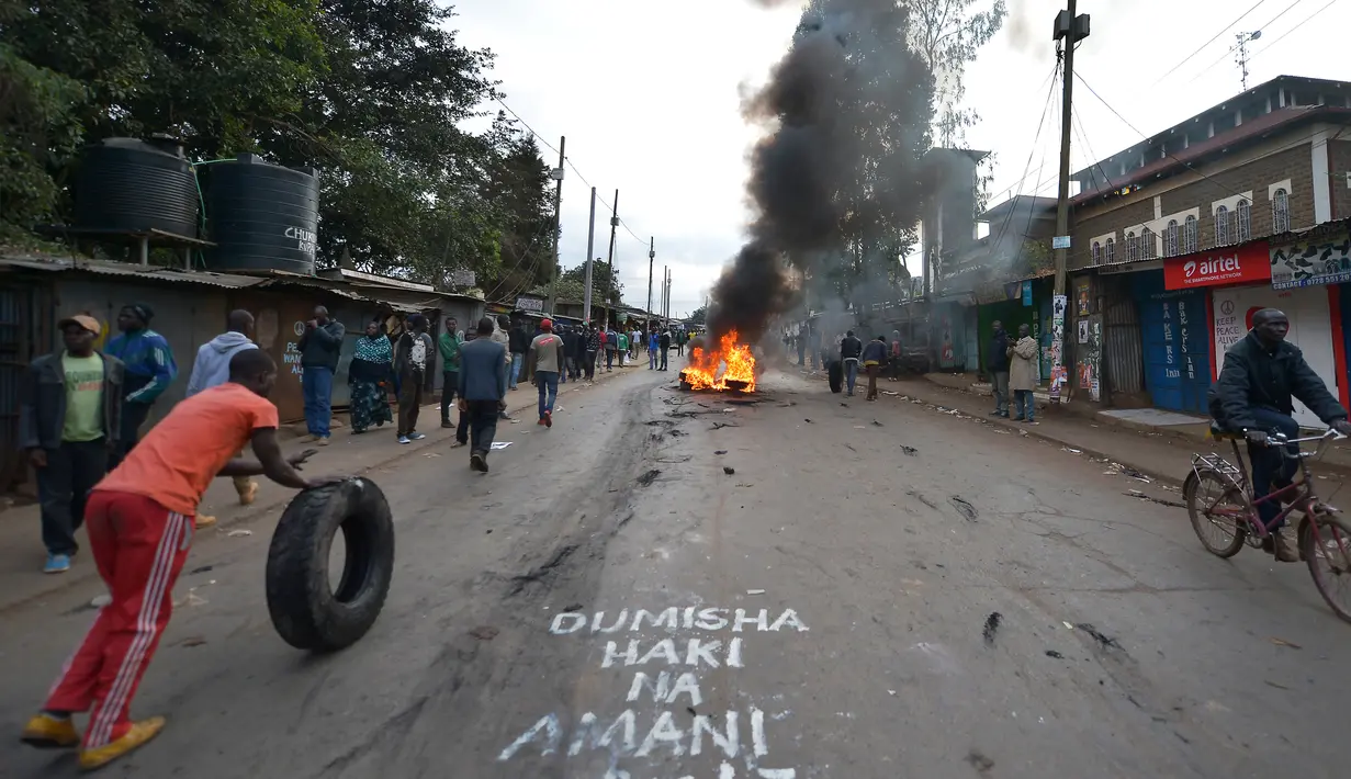 Massa membakar ban dan turun ke jalan saat menggelar protes terkait pemilihan presiden Kenya di Kibera, Nairobi, Kenya (9/8). Kerusuhan terjadi setelah badan pemilihan menyatakan Uhuru Kenyatta sebagai pemenang pemilihan presiden. (AFP Photo/Tony Karumba)