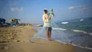 Nelayan Palestina, Jihad al-Soltan mencari ikan dengan melempar jala di pantai kawasan Beit Lahia, Jalur Gaza, Selasa (22/8). Soltan menemukan botol surat yang dihanyutkan pasangan Inggris yang tengah berlibur di Pulau Rhodes, Yunani. (MOHAMMED ABED/AFP)