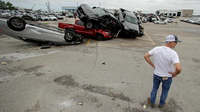 Seorang pekerja melihat-lihat mobil yang rusak akibat tornado di sebuah dealer di Jefferson City, Missouri, AS, Kamis (23/5/2019). Tornado juga menghantam ibu kota negara bagian, membawa hujan lebat, hujan es, angin, dan kilat. (AP Photo/Charlie Riedel)