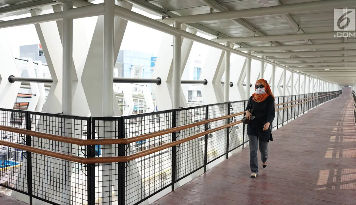 Warga melintasi jembatan penyeberangan (Skybridge) yang menghubungkan Stasiun LRT Velodrome dengan Halte Transjakarta Pemuda di Rawamangun, Jakarta, Senin (29/7/2019). Skybridge ini bertujuan memudahkan integrasi penumpang LRT menuju Transjakarta atau sebaliknya. (Liputan6.com/Immanuel Antonius)