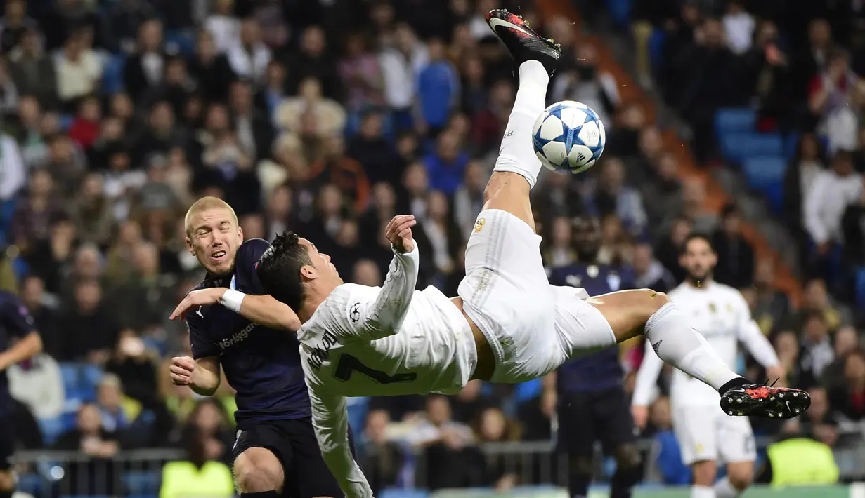 Pemain Real Madrid, Cristiano Ronaldo (kanan) melakukan tendangan salto melewaati pemain Malmo FF, Anton Tinnerholm  pada lanjutan Liga Champions Grup A di Stadion Satiago Bernabeu, Rabu (9/12/2015) dini hari WIB. (AFP Photo/ Pierre-Philippe Marcou)
