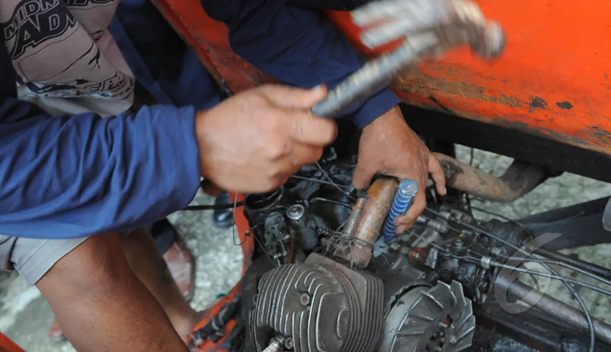 Pekerja memisahkan mesin dari kerangka bajaj. Rencananya bajaj orange akan dimusnahkan dan diganti Bajaj biru berbahan bakar gas (BBG), Jakarta, Rabu (4/3/2015). (Liputan6.com/Herman Zakharia)