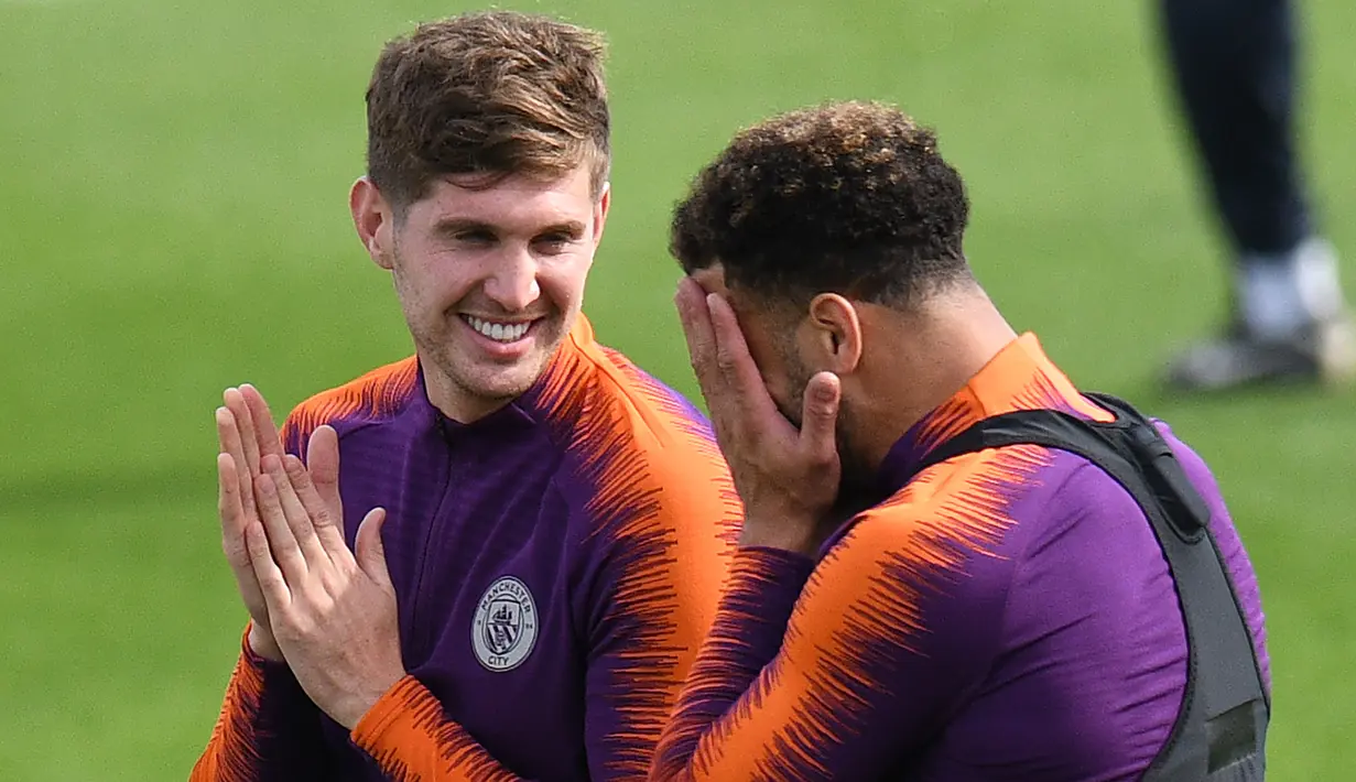 Bek Manchester City, John Stones berbincang dengan Kyle Walker selama sesi pelatihan tim di City Football Academy, Inggris (18/9). City akan bertanding melawan wakil Prancis, Lyon pada grup F Liga Champions. (AFP Photo/Oli Scarff)