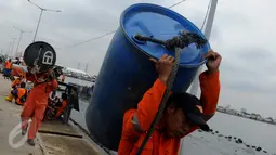 Petugas Basarnas membawa drum kosong untuk mengangkat bangkai kapal Zahro Express di Pelabuhan Muara Angke, Jakarta, Rabu (4/1). Puluhan drum kosong dipasang di sekeliling bangkai kapal untuk mengangkat kapal perlahan-lahan. (Liputan6.com/Gempur M Surya)