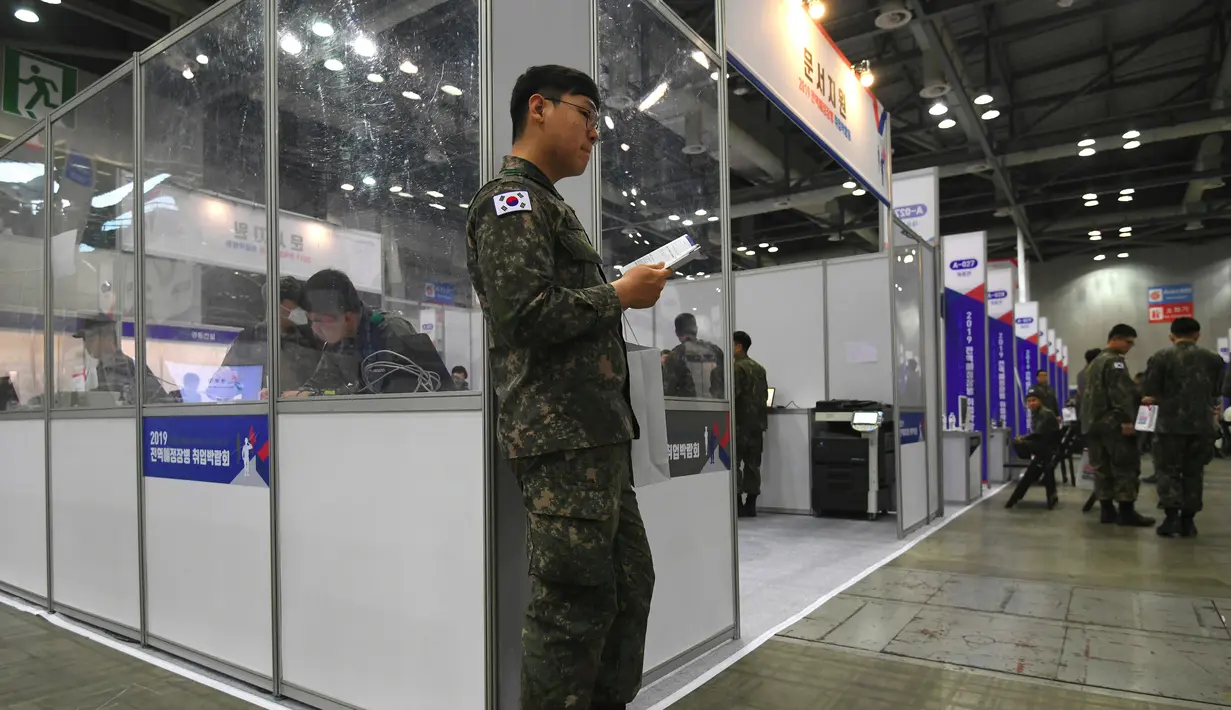 Tentara Korea Selatan membaca buku panduan saat mengikuti job fair di ruang pameran KINTEX, Goyang, Korea Selatan, Rabu (20/3). Job fair yang diselenggarakan oleh Kementerian Pertahanan Korea Selatan ini diikuti 200 perusahaan. (JUNG Yeon-Je/AFP)