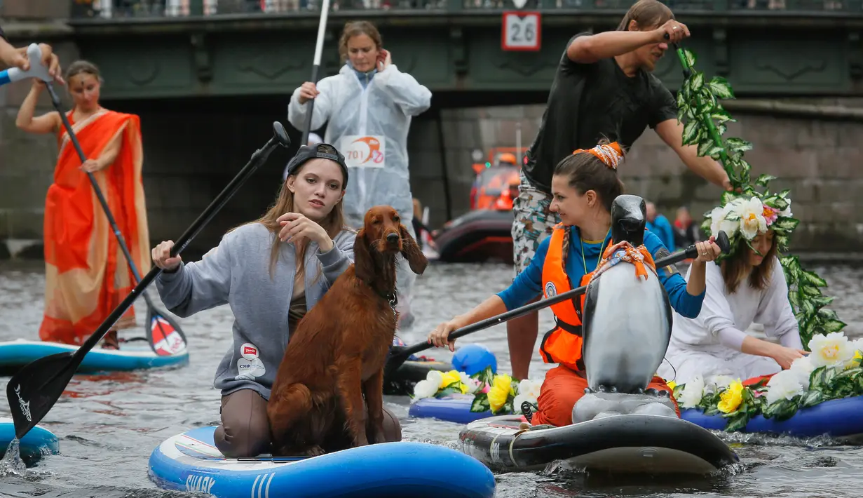Seorang wanita membawa anjingnya mendayung "paddle board" di kanal Griboedov pada festival SUP (Stand Up Paddle)-Surfing di St.Petersburg, Rusia, Minggu (12/8). Dalam paddling, papan digerakkan dengan cara mendayung sambil berdiri. (AP/Dmitri Lovetsky)