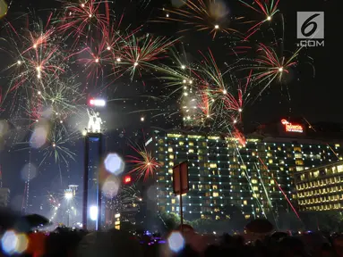 Kembang api menghiasi malam pergantian tahun baru 2019 di kawasan Bundaran HI, Jakarta, Selasa (1/1). Hujan yang mengguyur Jakarta tidak menyurutkan warga menikmati kembang api tahun baru. (Liputan6.com/Angga Yuniar)