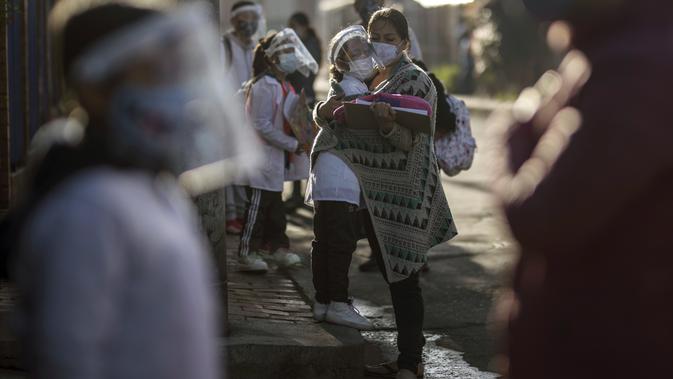 Orang tua menemani anaknya untuk memasuki Liceo Lunita, sebuah sekolah swasta, pada hari pertama kembali ke kelas tatap muka sejak Maret 2020 di Chia di pinggiran Bogota, Kolombia, Jumat (5/2/2021). Sejauh ini Kolombia melaporkan lebih dari 2,13 juta kasus Covid-19. (AP Photo/Ivan Valencia)