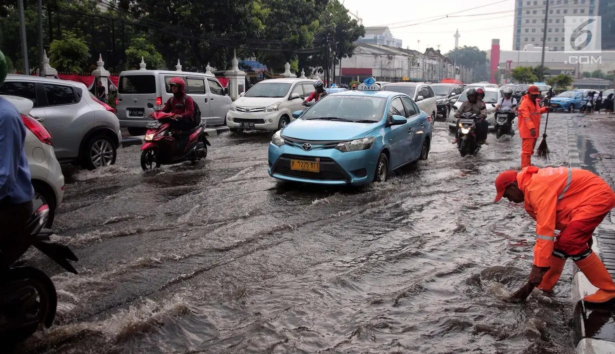 Sejumlah kendaraan melintasi genangan air usai hujan deras dikawasan Tugu Tani, Jakarta, Kamis (12/10). Agar tidak terjadi genangan kembali petugas dari Dinas Kebersihan membuang aliran air hujan kedalam selokan. (Liputan6.com/Faizal Fanani)