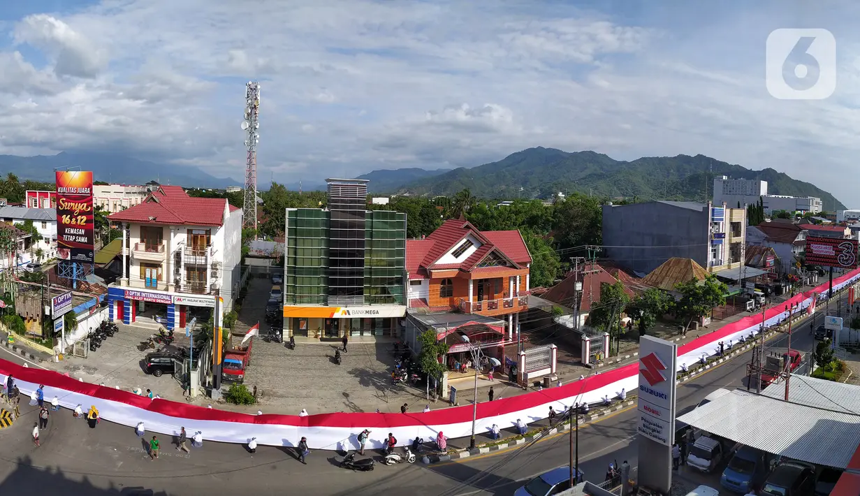 Pelajar SMA membentangkan bendera Merah Putih sepanjang 2,3 kilometer di Jalan Panjaitan dan Jalan Nani Wartabone, Gorontalo, Kamis (23/1/2020). Acara tersebut dilakukan untuk mengenang 78 tahun Hari Patriotik. (Liputan6.com/Arfandi Ibrahim)