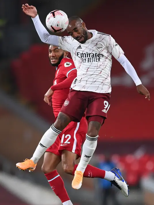 Bek Liverpool, Joe Gomez berebut bola dengan penyerang Arsenal, Alexandre Lacazette pada pekan ketiga Liga Inggris di Anfield, Selasa dinihari WIB (29/9/2020). Tertinggal lebih dulu, Liverpool mampu membungkam Arsenal dengan skor 3-1. (Laurence Griffiths/Pool via AP)