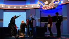 Pekerja membersihkan panel plastik pelindung di atas panggung di antara meja untuk Wakil Presiden Mike Pence dan penantangnya, Kamala Harris, saat persiapan untuk debat cawapres di Kingsbury Hall di Universitas Utah, Salt Lake City, Selasa (6/10/2020). (AP Photo/Patrick Semansky)