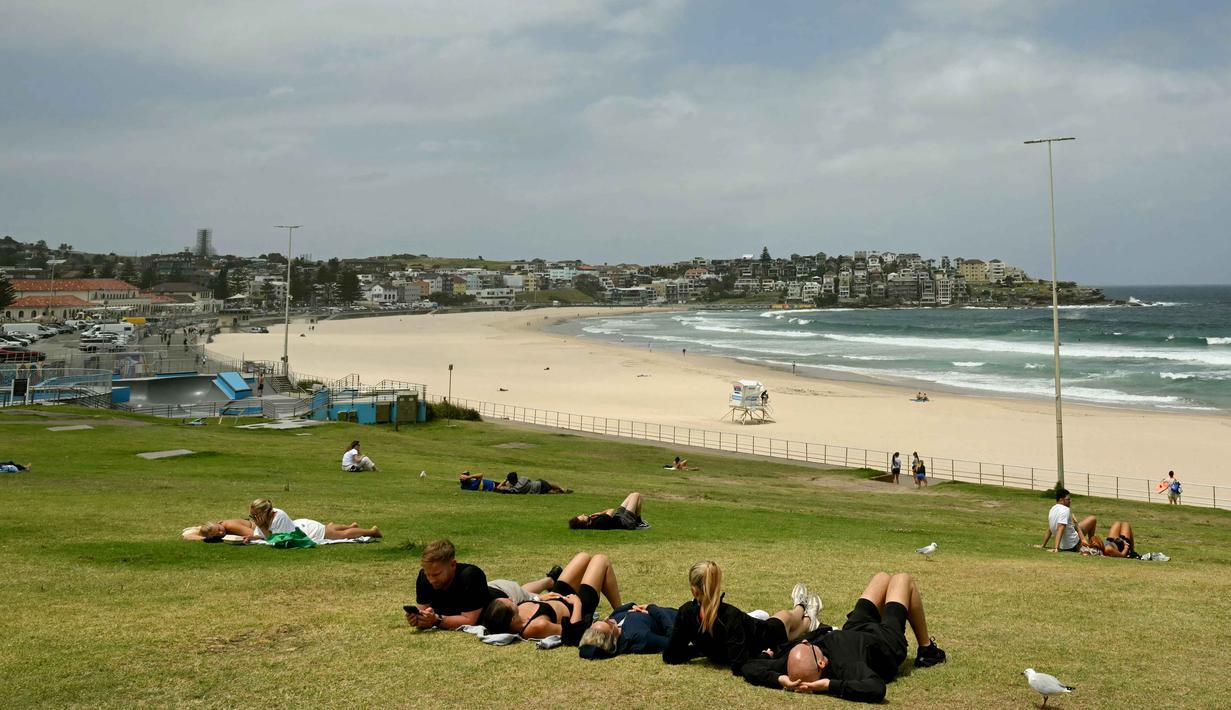 Sebelumnya, dua pelaku bersenjata, yang diyakini merupakan ayah dan anak, melepaskan tembakan saat ribuan warga Yahudi merayakan Hanukkah. Tampak dalam foto, orang-orang terlihat di Pantai Bondi, Sydney, Australia pada Senin 15 Desember 2025. (Saeed KHAN/AFP)
