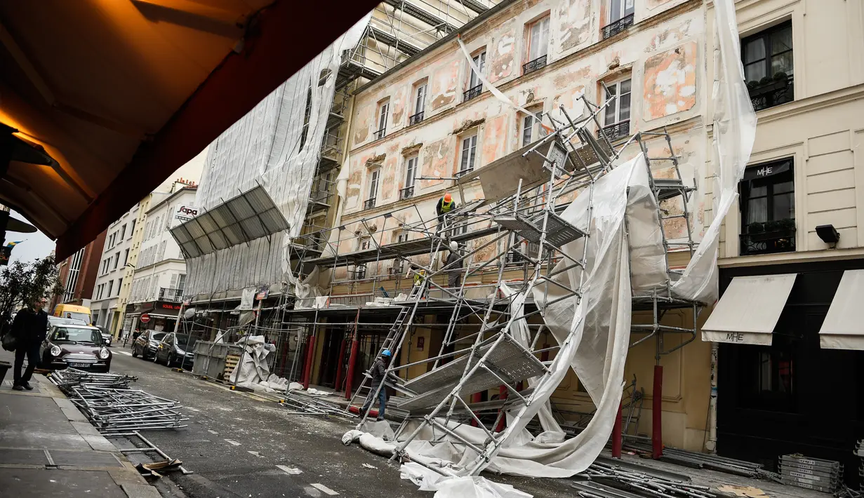 Pekerja melihat kerusakan yang terjadi usai penyangga proyek bangunan ambruk terkena angin kencang di Paris, Prancis (3/1). Tidak ada korban jiwa akibat jatuhnya penyangga proyek ini. (AFP Photo/Stephane De Sakutin)