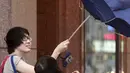 Warga taiwan memegang payung yang rusak akibat tiupan angin kencang saat Topan Soudelor mendekati wilayah Taipei, Taiwan, (7/8/2015). Topan ini diperkirakan akan melanda wilayah Taiwan pada hari Sabtu. (REUTERS/Pichi Chuang)