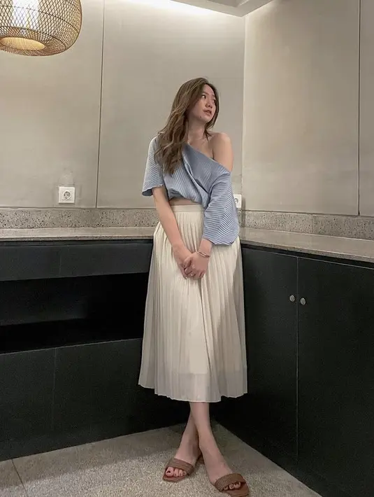 Untuk gaya fashion lainnya, nampaknya Shanju kerap memamerkan pundak indah. Misalnya ia mengenakan one off shoulder top warna biru berbahan plisket seperti maxi skirt putihnya. Tampak santai mengenakan sandal cokelat. @shanju.