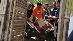 Tersangka Agus Dermawan saat bersiap mengendarai motor untuk membawa mayat korban di dalam kardus, Jakarta, Selasa (20/10/2015). Proses rekonstruksi pembunuhan bocah dalam kardus  menjadi tontonan warga sekitar. (Liputan6.com/Gempur M Surya)