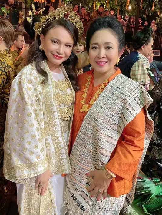 Titiek juga memadukan ulos dengan baju kurung orange dengan kalung panjang warna keemasan. Dengan gaya rambut sanggulnya.  [@titieksoeharto]