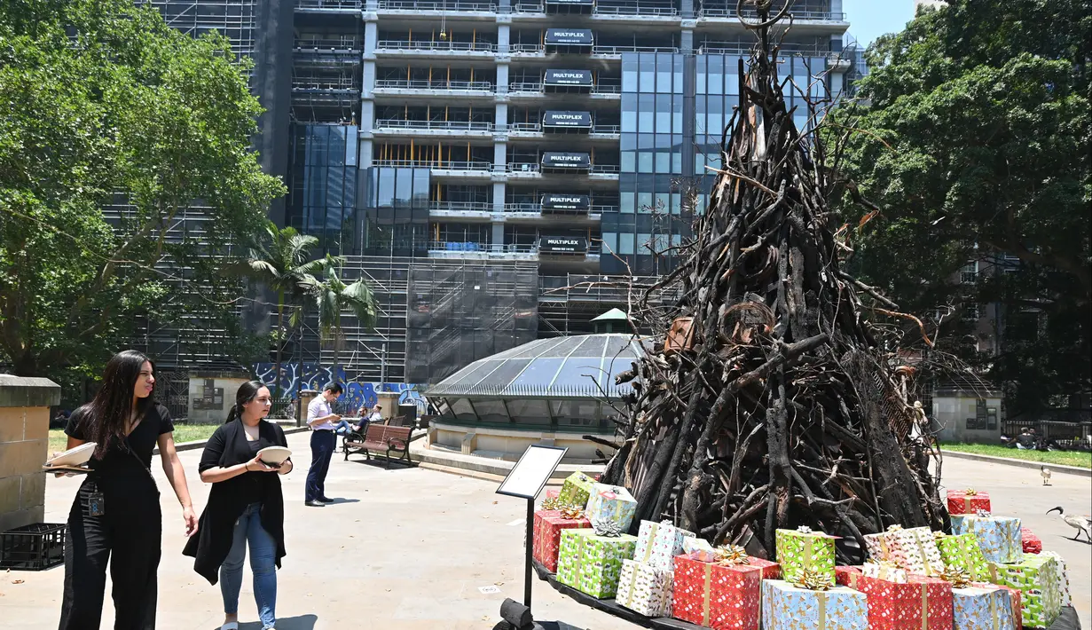 Dua wanita melihat instalasi yang dijuluki 'Pohon Natal yang Terbakar' di Sydney (18/12/2019). Instalasi Pohon Natal ini untuk mendukung Dana Bantuan dan Pemulihan Bencana Palang Merah Australia di tengah situasi kebakaran hutan. (AFP/Peter Parks)