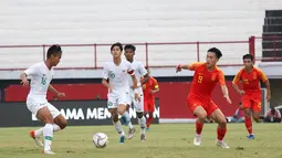 Bek Timnas Indonesia U-19, Komang Teguh  berusaha mengamankan bola dari striker China U-19, Junxian Liu, pada laga ujicoba di Stadion I Wayab Dipta, Bali, Minggu (20/10). Indonesia kalah 1-3 dari China. (Bola.com/Aditya Wany)