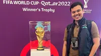 Jurnalis Bola.com, Ade Yusuf Satria foto bareng dengan trofi asli Piala Dunia 2022. (Istimewa)