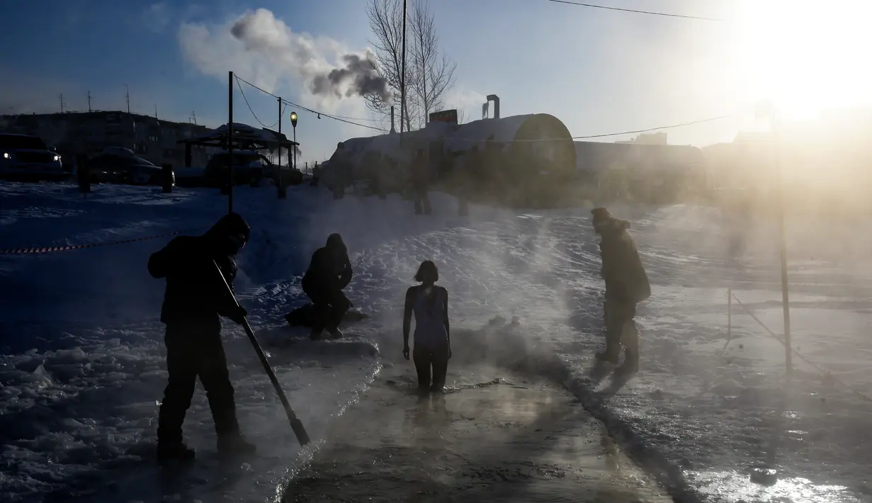 Seorang anggota klub renang es bersiap untuk berenang ke dalam air sedingin es saat suhu turun hingga minus 34 derajat celsius, di Novosibirsk, Rusia, Sabtu (26/12/2020). Saat musim dingin datang, warga di Rusia justru mendatangi air yang dingin untuk berenang. (Rostislav NETISOV/AFP)